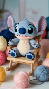 A crocheted stuffed Stitch toy resembling a blue alien-like creature sitting on a small wooden rocking chair, surrounded by balls of colorful yarn.