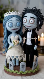 Crocheted figurines of a bride and groom with skeletal features, standing on a round base decorated with small tombstones and green edging.