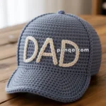 A blue crocheted baseball cap with the word "DAD" stitched in white yarn on the front, resting on a wooden table.