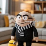 Crocheted Gru doll resembling a bald character in a black outfit with a striped scarf, standing next to a small yellow crocheted figure with one eye, on a wooden table in a living room setting.