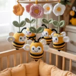 A baby mobile above a crib featuring crocheted bees and flowers suspended from a wooden ring.