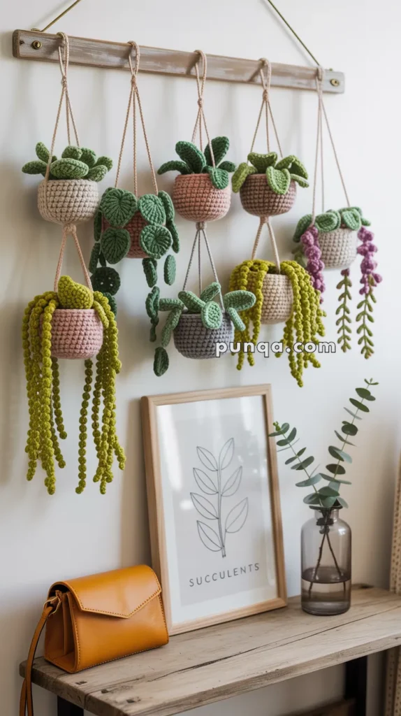 Crocheted hanging planters with green leaves and colorful stems displayed on a wooden shelf, next to a framed botanical print and a small amber handbag.