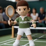 A crocheted tennis player doll standing on a tennis court, holding a racket in one hand, with a green and white outfit and an audience blurred in the background.