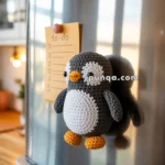 A crocheted penguin magnet is attached to a stainless steel refrigerator, next to a to-do list held by a red magnet.