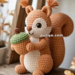 A crocheted squirrel plushie holding a green acorn, placed on a wooden shelf with autumn leaves in the background.
