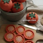 Crocheted tomatoes in a basket and handmade tomato slices on a wooden board with a knife.