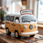 A crocheted model of a yellow vintage van with a "Wanderlust" sign on top, placed on a wooden table.