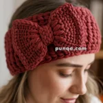 A woman wearing a maroon crocheted headband with a large bow, seen in profile.
