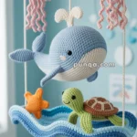 A crochet mobile featuring a blue whale, a green turtle, and a starfish on a wave, with pink jellyfish hanging above them, set in a light blue room.