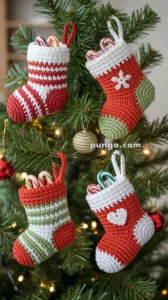 Four crochet Christmas stockings in red, white, and green, each filled with candy canes, hanging on a decorated Christmas tree.