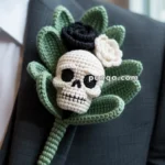 Crocheted boutonniere featuring a skull design with green leaves and black and white flowers, pinned to a dark suit.